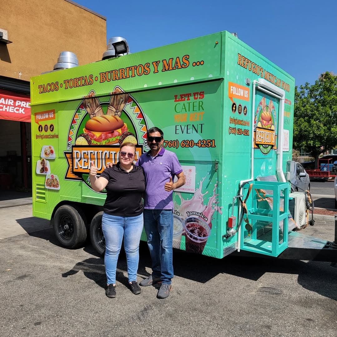 Owners of Refugio's Mexican Food in front of their wrapped trailer