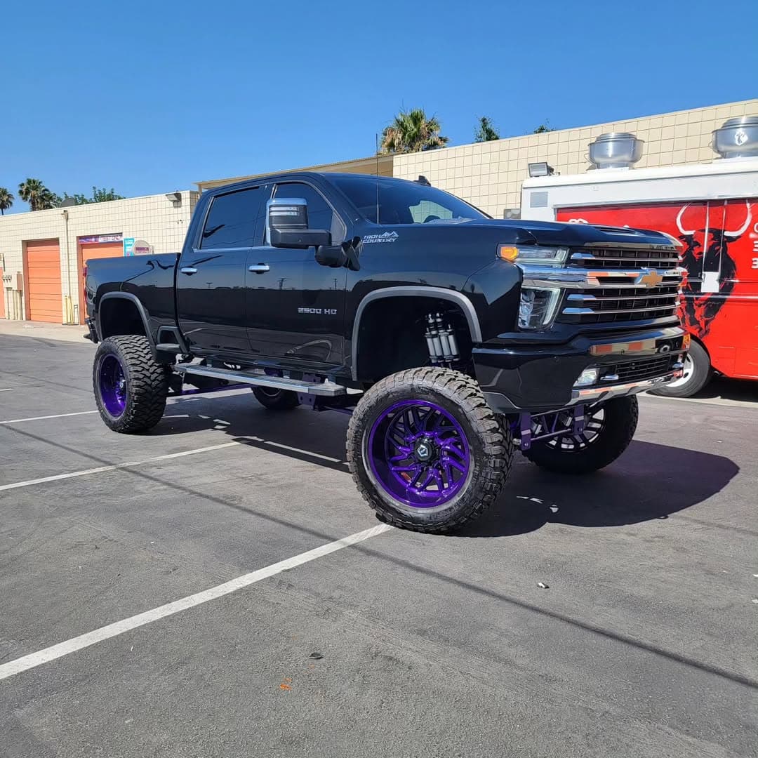 Lifted black Chevrolet Silverado 2500HD with purple custom wheels